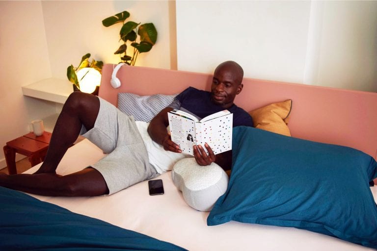 Man reading in bed; bamboo nightstands