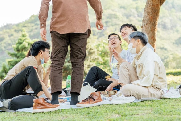 Friends at a picnic laughing; bamboo cutlery