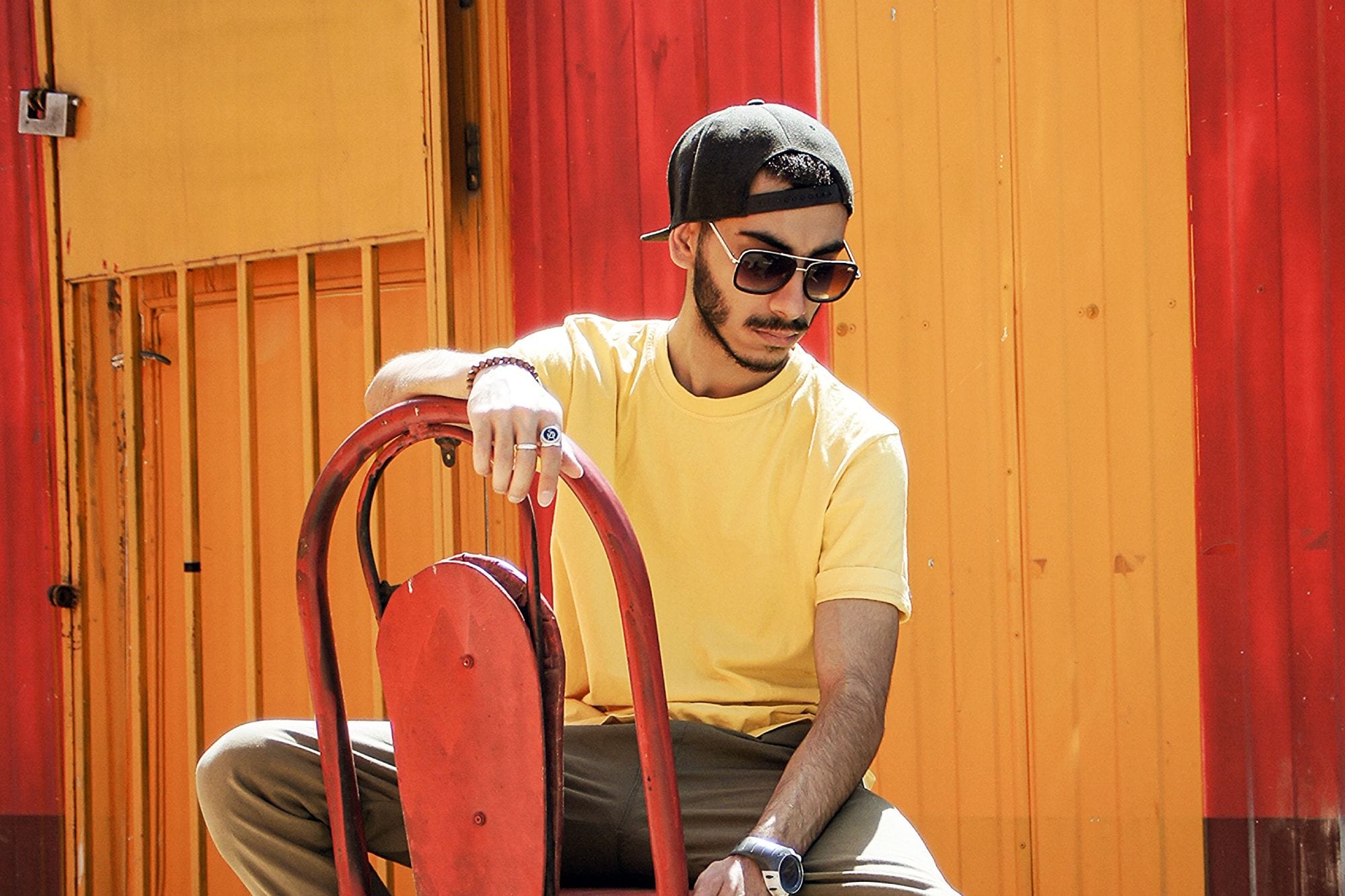 Man sitting on chair outside wearing bamboo sunglasses