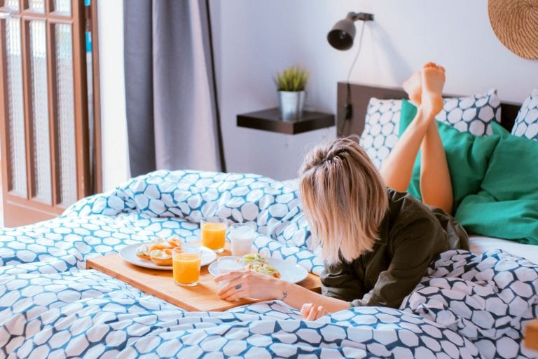 Woman eating breakfast on bed; bamboo bed frames