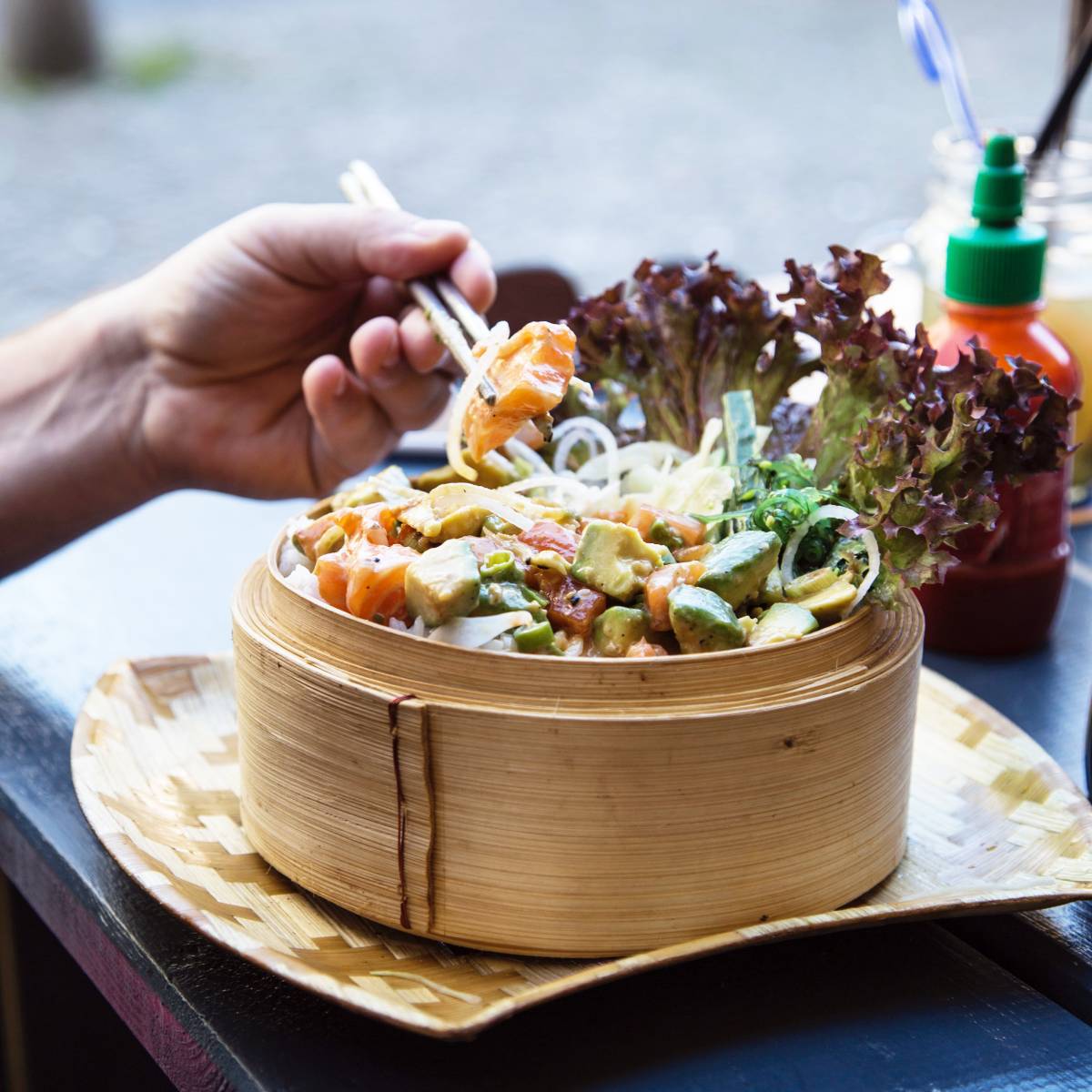 Person eating vegetables from a bamboo steamer