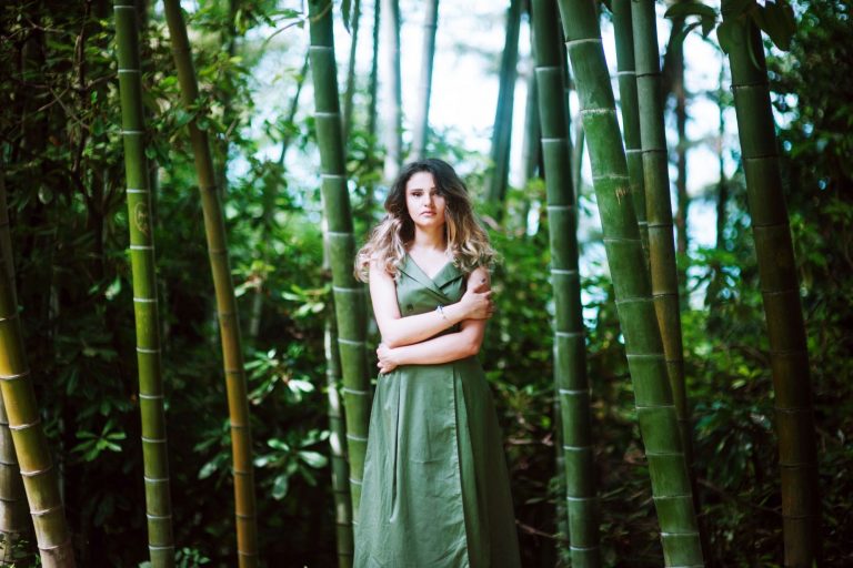 Woman standing in sustainable bamboo grove folding her arms