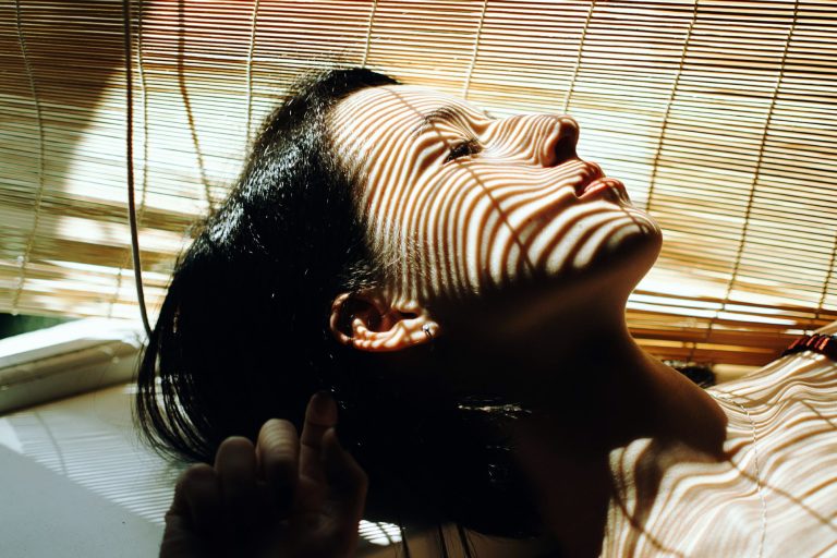 Woman sleeping near bamboo blinds in sunlight