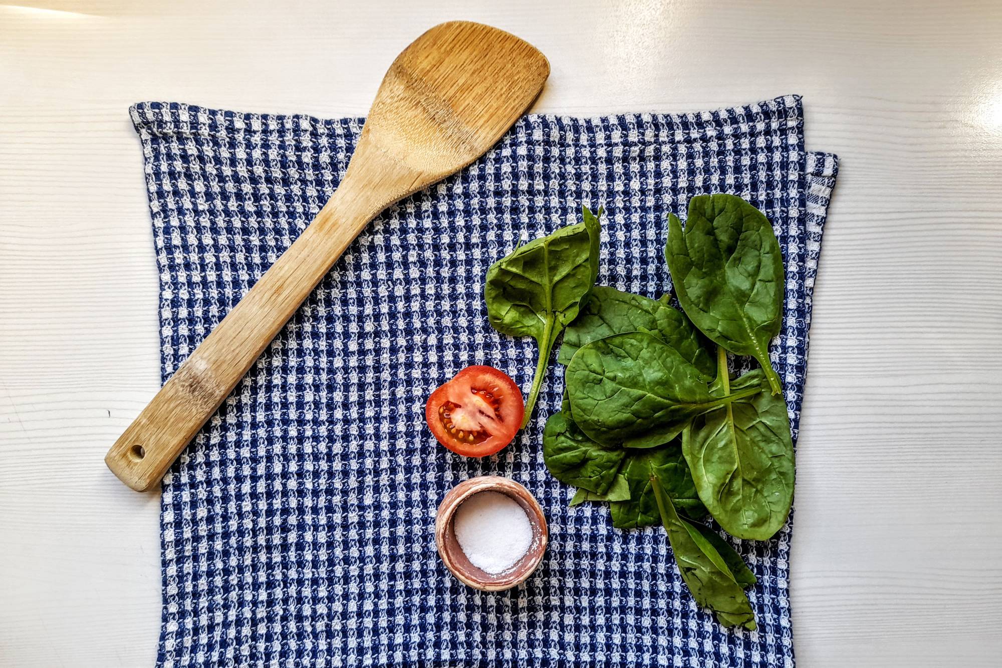 Bamboo spoon on a cloth next to salad ingredients