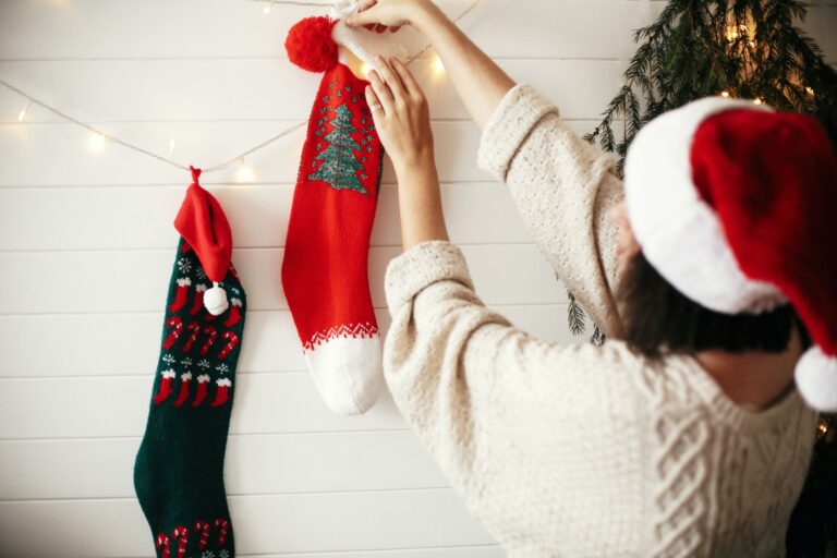 Woman wearing a Santa hat hanging Christmas stockings
